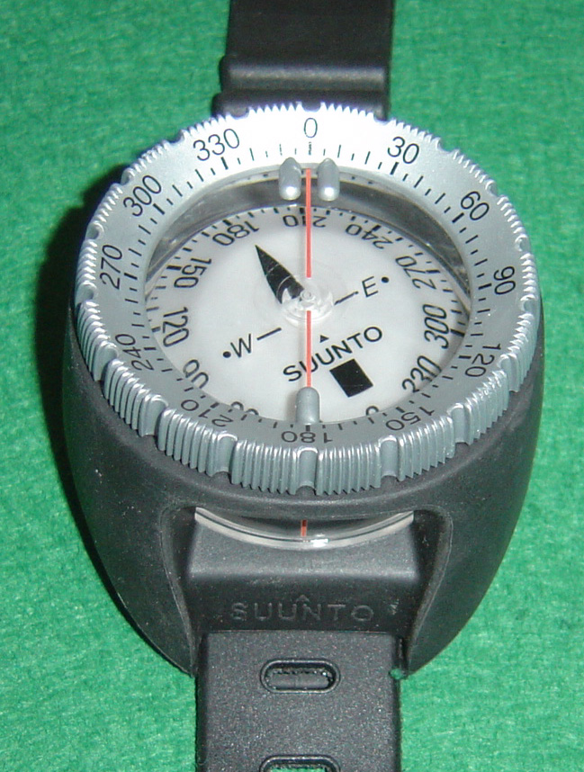 Close view of an analog underwater compass with rotating bezel, index marks, card and lubber line visible